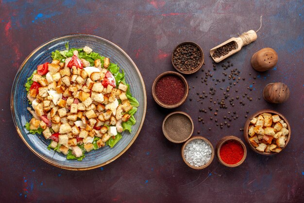 Вид сверху вкусный салат цезарь с приправами на темном столе