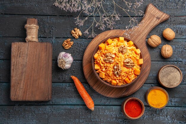 Top view tasty carrot salad with walnuts and seasonings on dark blue desk salad nut health color food diet