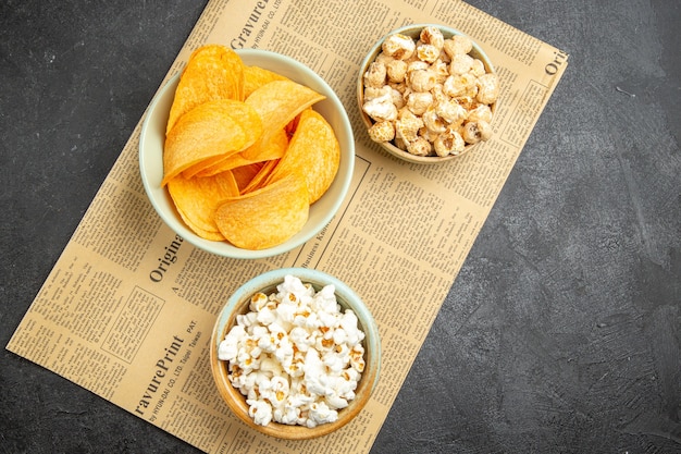 Вид сверху вкусные сырные чипсы с разными закусками для просмотра фильмов на темном фоне