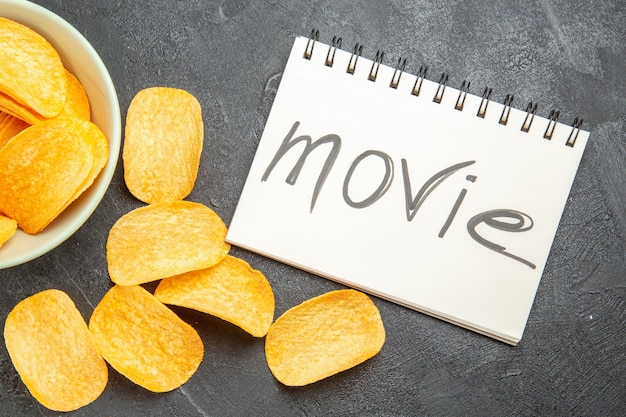 Free photo top view tasty cheese cips inside plate with movie written notepad on grey background