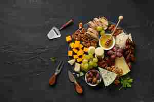 Foto gratuita vista dall'alto di un gustoso piatto di formaggio con frutta, uva, noci e miele su un piatto da cucina circolare sullo sfondo di pietra nera, vista dall'alto, copia spazio. cibo e bevande gourmet.