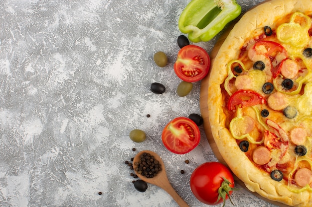 Top view tasty cheesy pizza with olives sausages and red tomatoes on the grey background fast-food italian dough meal