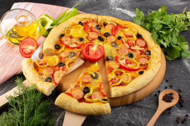 Вид сверху вкусная сырная пицца с красными помидорами, черными оливками, зеленью и сосисками на темном столе, фаст-фуд, выпечка из итальянского теста