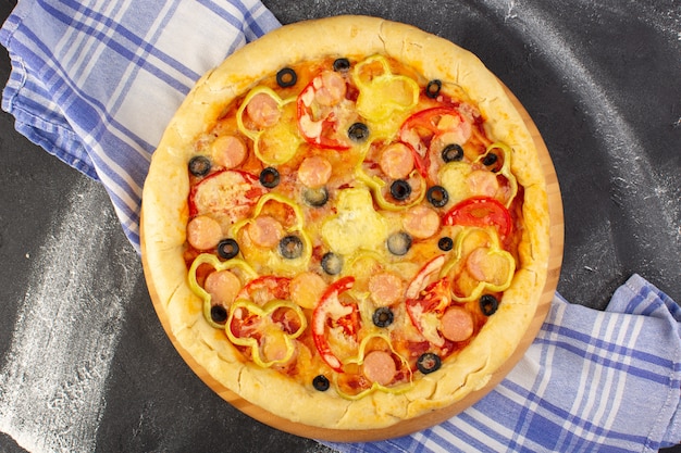 Top view tasty cheesy pizza with red tomatoes black olives and sausages on the dark background with towel fast-food meal italian dough