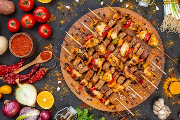 Top view tasty chicken kebab on wooden serving board and other stuffs on table
