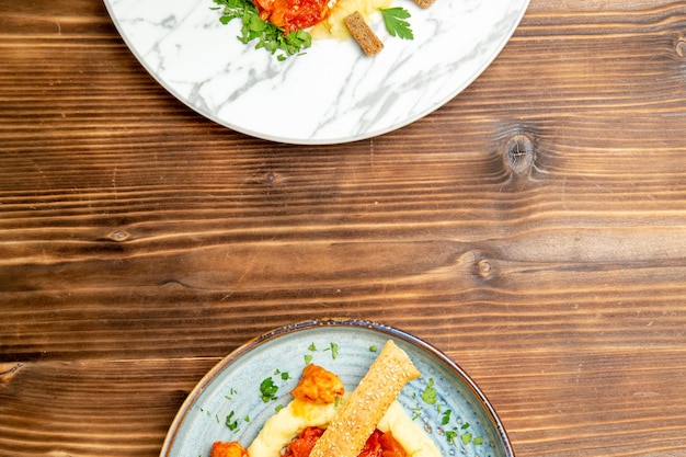 Top view of tasty chicken slices with mushed potatoes on brown table