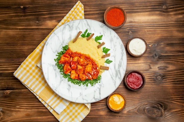 갈색 테이블에 mushed 감자와 조미료와 함께 맛있는 치킨 조각의 상위 뷰