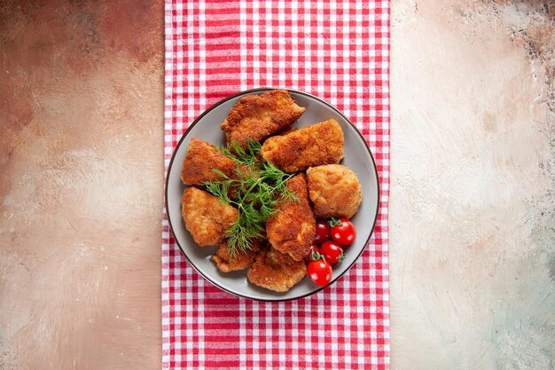 Top view tasty chicken wings with greens and tomatoes on light surface