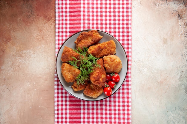 Вид сверху вкусные куриные крылышки с зеленью и помидорами на светлой поверхности