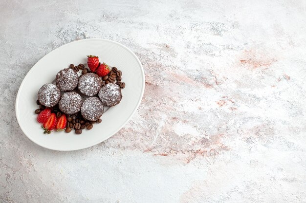 Top view tasty chocolate cakes with strawberries and chocolate chips on light-white surface