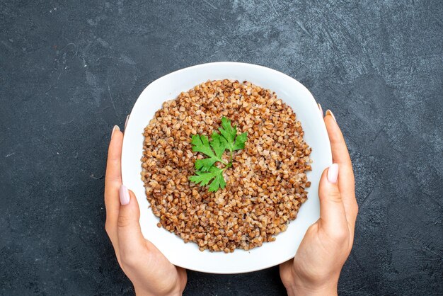 Top view tasty cooked buckwheat inside plate on dark grey space