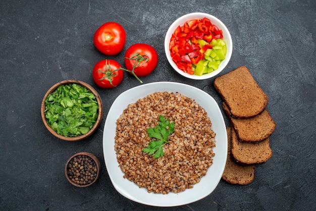 어두운 공간에 어두운 빵 덩어리와 채소와 함께 상위 뷰 맛있는 요리 메밀