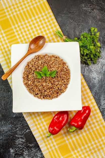 Free photo top view tasty cooked buckwheat with greens and bell-peppers on light-grey table