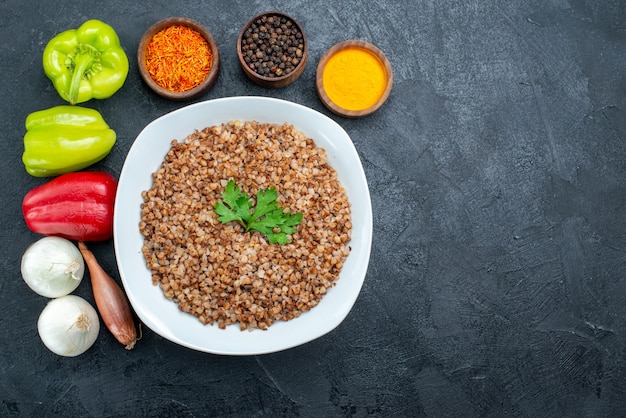 Free photo top view tasty cooked buckwheat with seasonings on grey