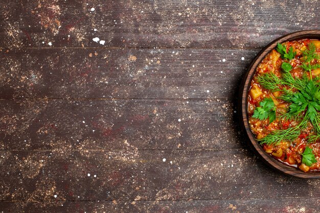 Top view tasty cooked meal consists of sliced vegetables and greens on brown desk meal sauce soup food vegetable calorie