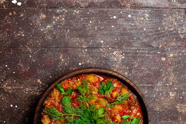 Vista dall'alto gustoso pasto cucinato composto da verdure a fette e verdure sul marrone rustico scrivania pasto salsa zuppa di verdure caloriche alimentari