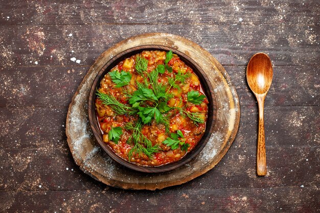 Top view tasty cooked meal consists of sliced vegetables and greens on a brown rustic desk meal sauce soup food