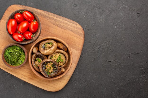 Top view tasty cooked mushrooms with red tomatoes on dark background