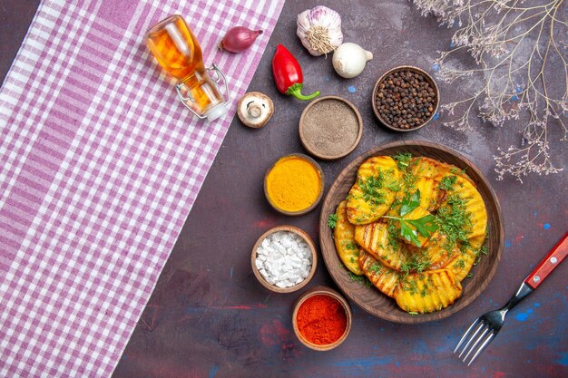 Foto gratuita vista dall'alto gustose patate cotte piatto delizioso con verdure e condimenti su una superficie scura che cucina un piatto di patate per la cena