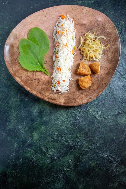 Top view tasty cooked rice with green leaves beans and meat inside plate on dark desk