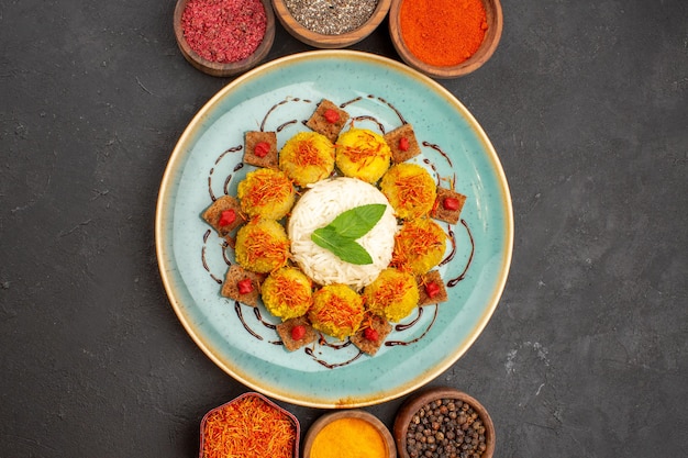 Top view of tasty cooked rice with meatballs and different seasonings on dark