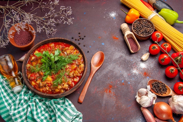 Вид сверху вкусной приготовленной овощной еды в соусе с разными приправами и помидорами на темном фоне