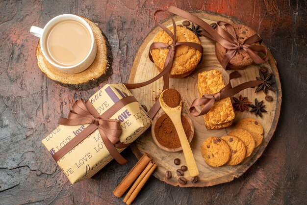 Top view tasty cookies tied with rope biscuits anises on wood board gift cup of coffee on dark red table