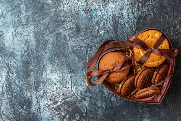 Free photo top view tasty cookies tied with rope in heart shaped box on dark background