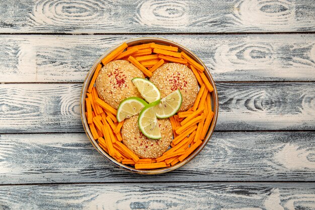 Top view tasty cookies with lemon slices and rusks on a grey desk biscuit sugar cake pie sweet cookie