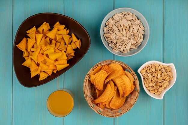 松の実とオレンジジュースのグラスとボウルに白いヒマワリの種が入ったバケツのおいしいクリスピーチップスの上面図