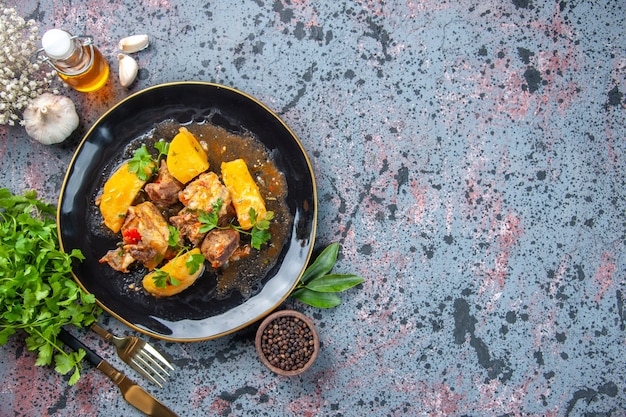 고기 감자와 함께 맛있는 저녁 식사의 상위 뷰는 검정 접시와 고추 마늘 기름 병 칼 세트에 녹색 제공