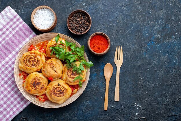 Вид сверху вкусной муки из теста с мясом внутри тарелки вместе с ложкой и вилкой для приправ на темном столе еда еда мясной овощ