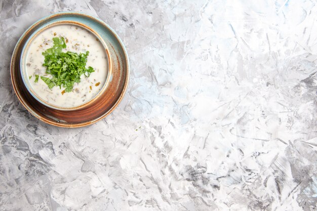 Top view tasty dovga yogurt soup with greens inside plate on the white table milk soup meal