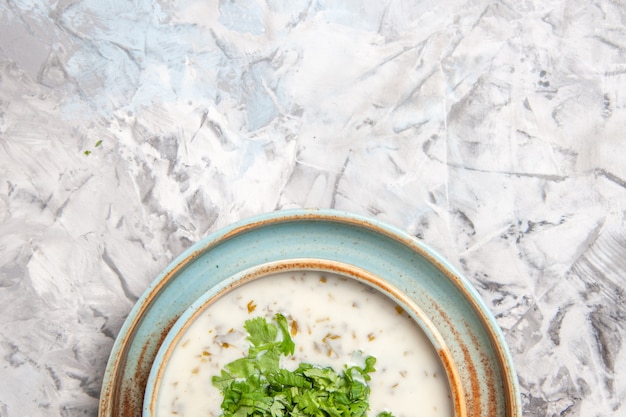 Бесплатное фото Вид сверху вкусный йогуртовый суп довга с зеленью на белом столовом молочном блюде