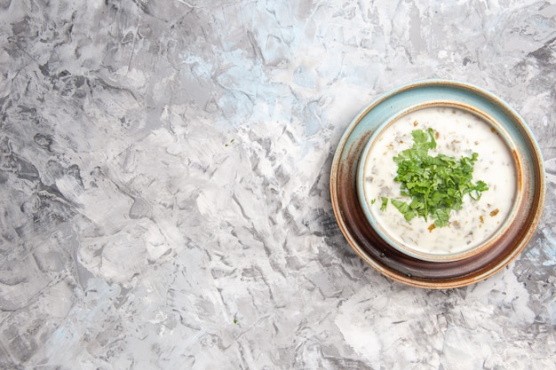 Top view tasty dovga yogurt soup with greens on a white table milk soup meal dish