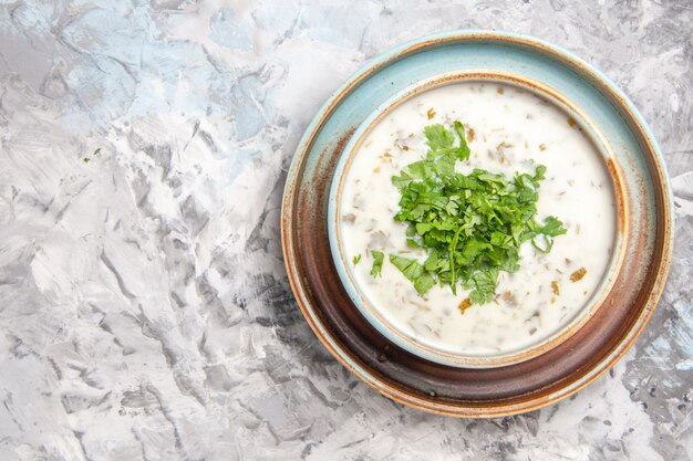 Top view tasty dovga yogurt soup with greens on the white table milk soup meal dish