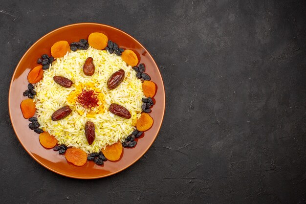 Top view tasty famous eastern meal consists of cooked rice and raisins on a dark