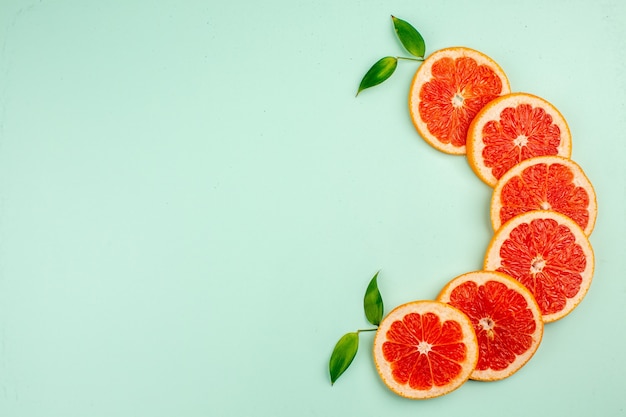 Top view of tasty fresh grapefruits juicy fruit slices on light-blue surface