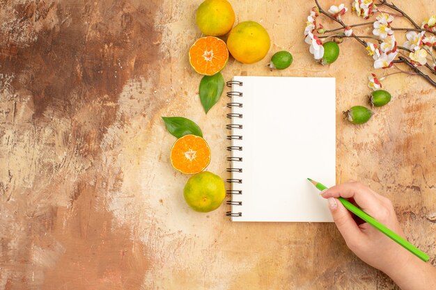 Top view tasty fresh tangerines with feijoas and notepad