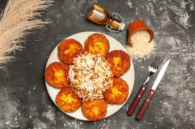 Top view tasty fried cutlets with cooked rice on a dark surface dish meal photo