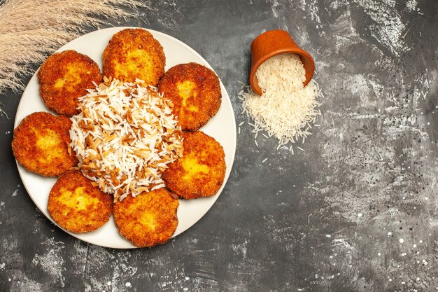 Top view tasty fried cutlets with cooked rice on the dark surface dish photo meat