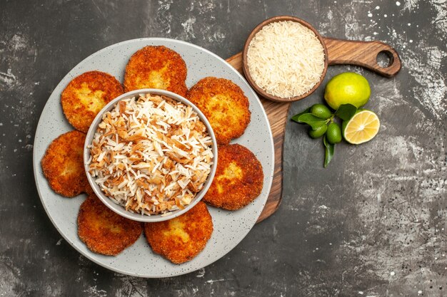 Top view tasty fried cutlets with cooked rice on the dark surface meat rissole dish