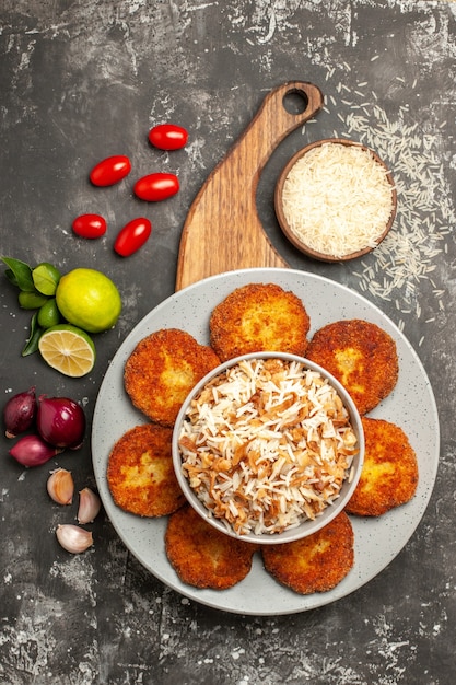 Top view tasty fried cutlets with cooked rice on dark surface meat rissole meal