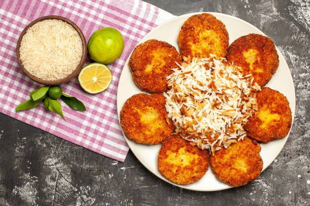 Top view tasty fried cutlets with cooked rice on the dark surface rissole meat food