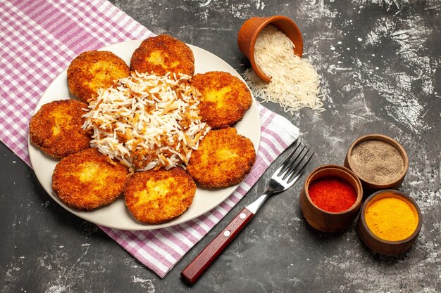 Top view tasty fried cutlets with cooked rice on dark surface rissole meat