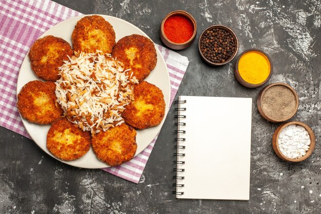 Top view tasty fried cutlets with rice and seasonings on dark desk food meat rissole