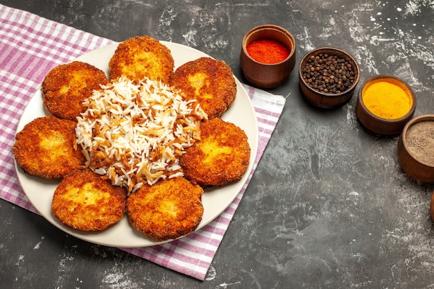 Foto gratuita vista dall'alto gustose cotolette fritte con riso e condimenti su polpetta di carne di cibo piano scuro