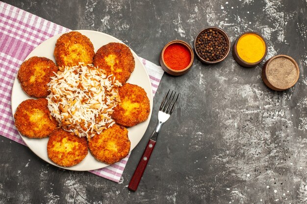 Top view tasty fried cutlets with rice and seasonings on dark surface meat rissole food