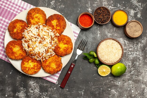 Top view tasty fried cutlets with rice and seasonings on the dark surface meat rissole food