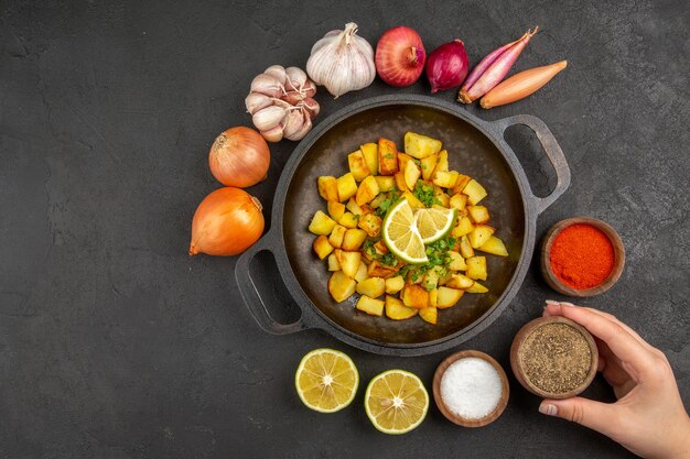 Free photo top view of tasty fried potatoes inside pan with different seasonings on dark surface